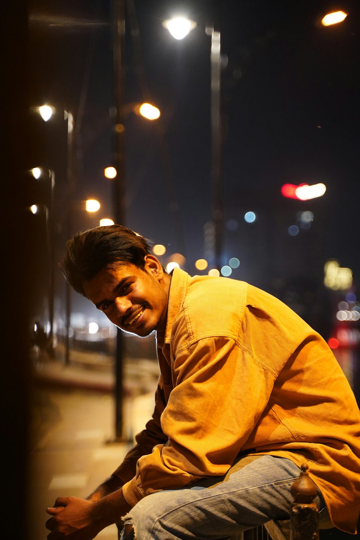 Homem sorrindo à noite com luzes da cidade ao fundo