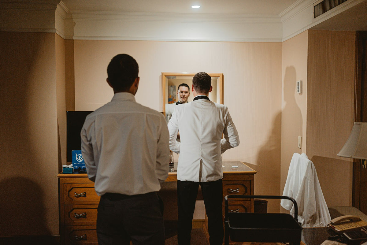 Homem de camisa branca se arrumando em frente ao espelho antes de sair, cheiroso o dia todo